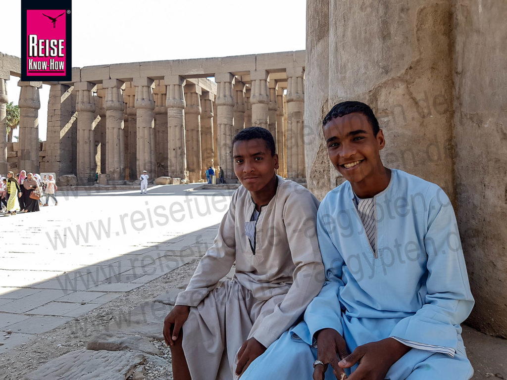 Zwei ägyptische Jungen in Galabiya sitzen an einer Säule im Luxor-Tempel